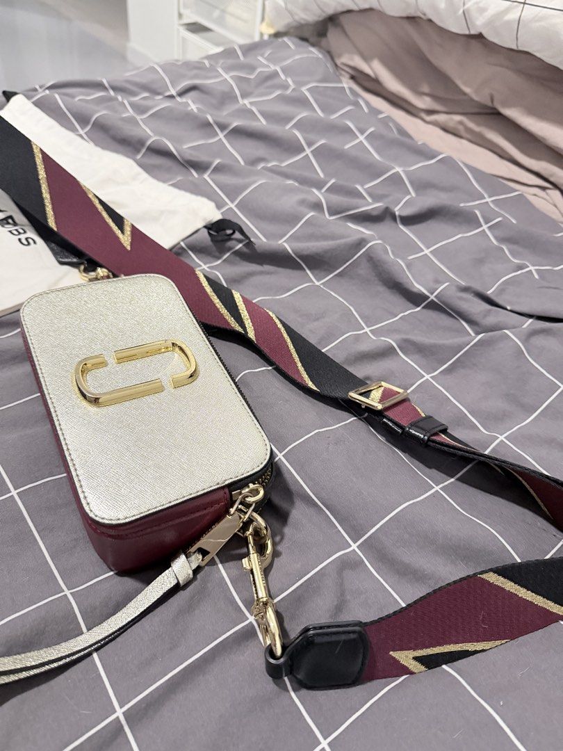 The Marc Jacobs Snapshot Camera Bag Silver Burgundy (Category: Luxury Bags & Wallets) located in Makati City. Submitted by purewind.a22dcd (Listing ID 1464861654, Image 1). Description: - Authentic Marc Jacobs Snapshot camera bag - Color: Silver and burgundy metallic - Material: Saffiano leather with gold-tone hardware and double J logo - Features: Dual zip compartments and wide patterned webbing strap - Inclusions: Dust bag and tags - Condition: