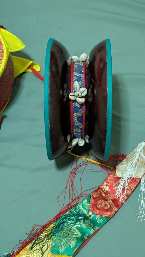 Tibetan Chod Damaru Drum with Case (Category: Musical Instruments) located in San Pedro. Submitted by leeeon_ (Listing ID 1464883985, Image 2). Description: - Item: Authentic Tibetan Chod damaru (double-headed ritual drum) I bought overseas - Condition: Clean and well-maintained overall - Appearance: Turquoise painted wooden shells adorned with cowrie shell ornaments - Accessories: Includes long colorful silk streamers with tassels - Storage: Com