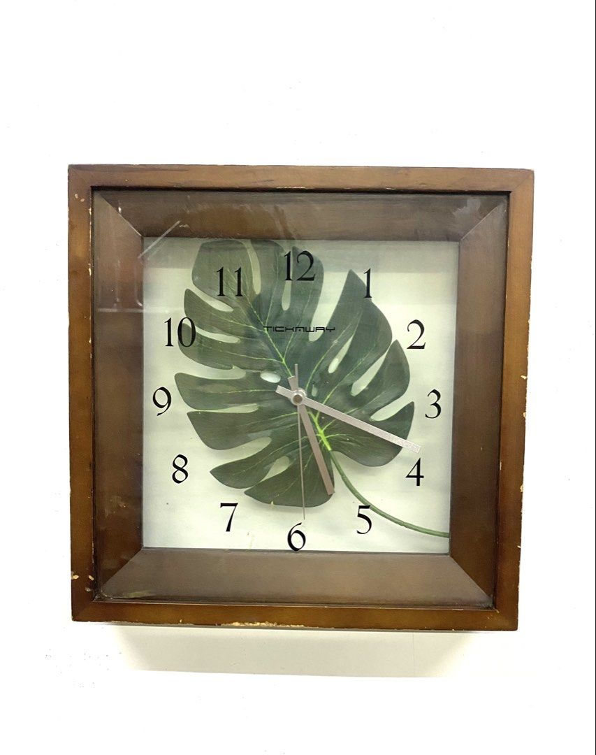 Tickaway Wooden Square Wall Clock with Monstera Leaf Design (Category: Clocks) located in Santa Rosa. Submitted by annie_annie83 (Listing ID 1464874005, Image 1). Description: - Brand: Tickaway - Design: Green Monstera leaf graphic on white background with clear black numbers - Materials: Brown wooden frame with a clear glass front cover - Mechanism: Battery-operated quartz movement - Condition: Good working condition with some scuffs and wear al