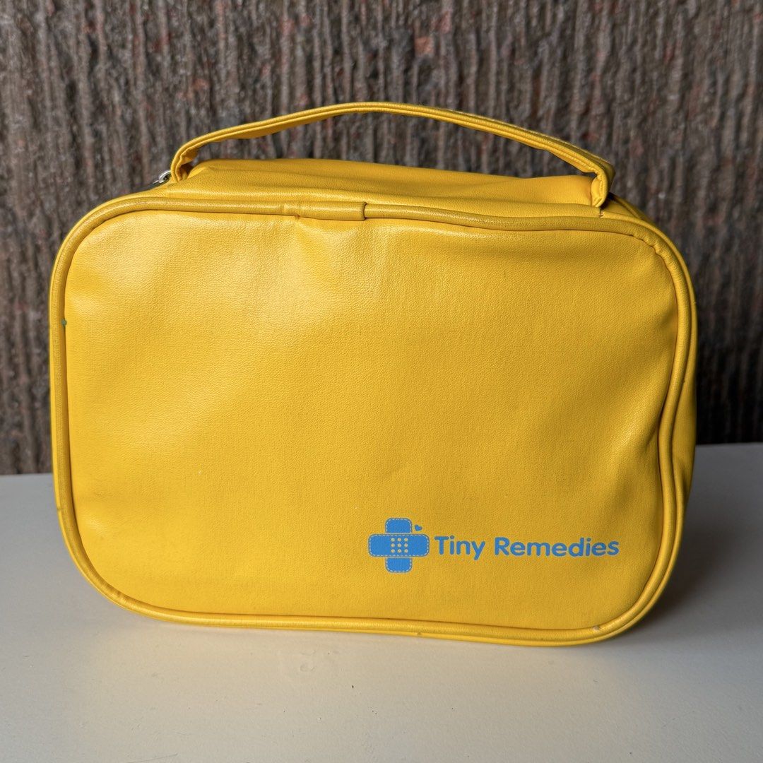 Tiny Remedies First Aid Kit Bag Yellow (Category: Luxury Bags & Wallets) located in Marikina City. Submitted by lovegoeson (Listing ID 1464856297, Image 3). Description: - Brand: Tiny Remedies - Design: Bright yellow with a cute cartoon bee and bandage on the front, plain yellow back with logo - Interior: Vibrant blue with mesh pockets, elastic bottle loops, and a secure zipped compartment - Portability: Features a convenient top handle for easy 