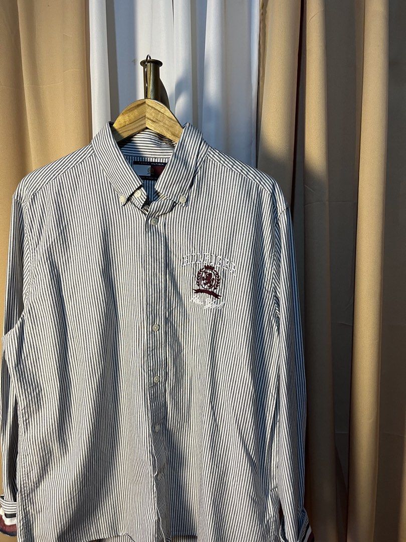 Tommy Hilfiger Classic Ithaca Stripe Shirt (Category: Tshirts & Polo Shirts ) located in Kidapawan. Submitted by azythrift (Listing ID 1464914496, Image 2). Description: - Brand: Tommy Hilfiger - Style: Long sleeve button-down shirt with classic point collar - Pattern: Blue and white vertical stripes - Size: Large - Material: 100% premium cotton - Details: Large embroidered crest logo on the chest, button cuffs with inner stripe detail - Conditio