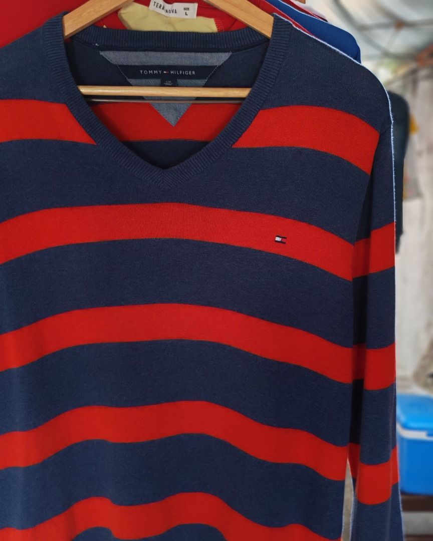 Tommy Hilfiger Striped V-Neck Sweater (Category: Coats, Jackets and Outerwear) located in Quezon City. Submitted by drift_and_vibe_thrift (Listing ID 1464873092, Image 2). Description: - Brand: Tommy Hilfiger - Style: V-neck sweater with navy blue & red horizontal stripes - Size: L - Material: 100% cotton (soft and comfortable) - Details: Long sleeves, ribbed hem, iconic embroidered flag logo on chest - Care: Machine washable - Condition: Excelle