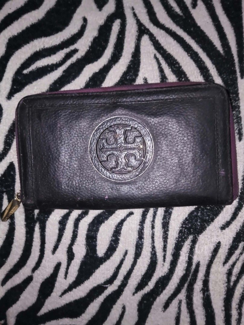 Tory Burch black leather zip-around wallet (Category: Luxury Bags & Wallets) located in Valenzuela. Submitted by rowenasalvador777 (Listing ID 1464968851, Image 1). Description: - Brand: Tory Burch - Material: Black leather with striking purple interior gusset - Hardware: Gold-tone zip-around closure and pull tab - Design: Large embossed logo on the front face - Storage: Multiple secure compartments for cards and cash - Condition: Shows noticeabl