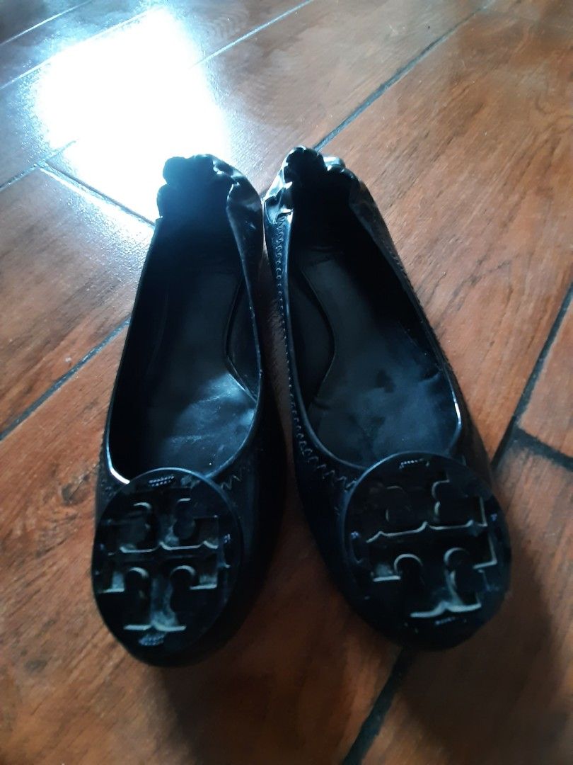 Tory Burch Flats (Category: Flats & Sandals) located in Castillejos. Submitted by lalainecloset22 (Listing ID 1464783831, Image 1). Description: - Brand: Tory Burch - Style: Black patent leather flats with round toes - Detail: Large iconic double T logo on the front - Comfort: Slip-on design with gathered elasticized heels and flexible rubber soles - Size: US 5 - Condition: Great for daily wear or travel packing -Made in Brazil .