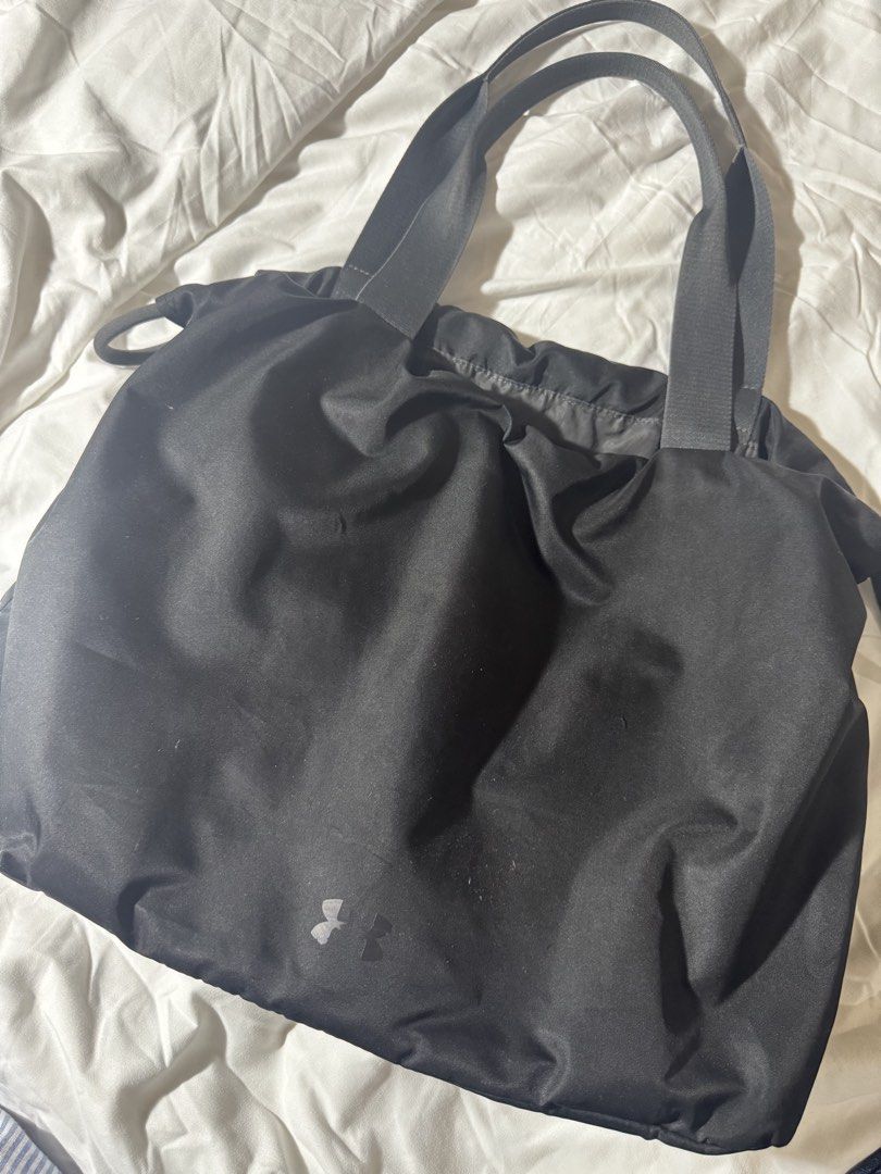 Under Armour Black Tote Bag (Category: Tote Bags) located in Bacolod City. Submitted by lovedandprelovedbygee (Listing ID 1464846163, Image 3). Description: - Brand: Under Armour - Color: Classic Black - Design: Large front brand print with a small logo near the bottom, stylish gathered top design - Straps: Comfortable double shoulder straps - Interior: Open main compartment with built-in slip pockets for easy organization - Material: Lightweight