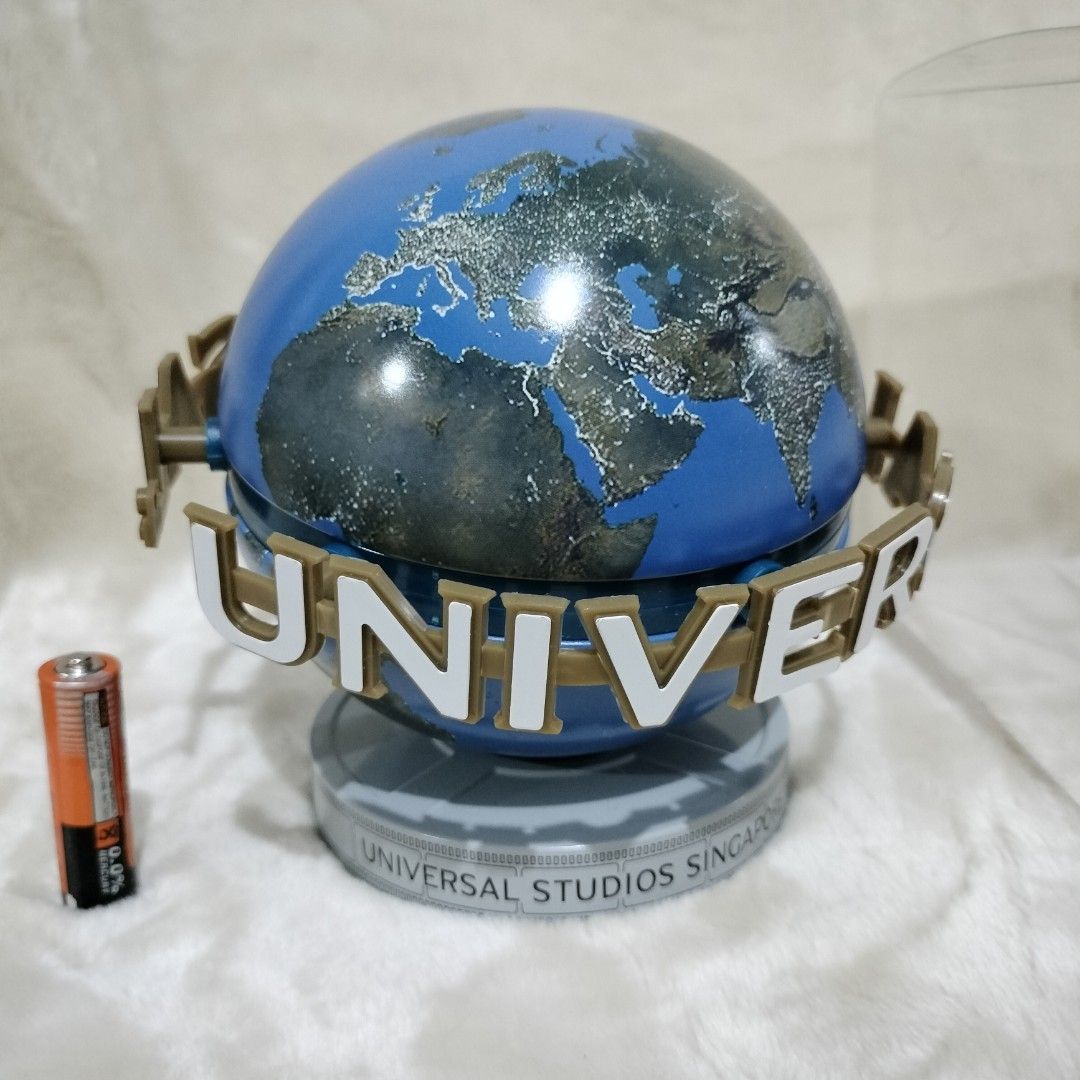 Universal Studios Singapore Souvenir Globe Cookie Tin Container (Category: Figurines & Statues) located in Imus. Submitted by viaysthriftshop (Listing ID 1464877524, Image 2). Description: ▪️Official Universal Studios Singapore merchandise ▪️New, unused item with slightly dented clear plastic display box ▪️Cookie Tin can container ▪️Height: 5.5 inches ▪️Features the iconic revolving-style globe design with the Universal logo ring 𝗠𝗢𝗣 ▪️GCash @