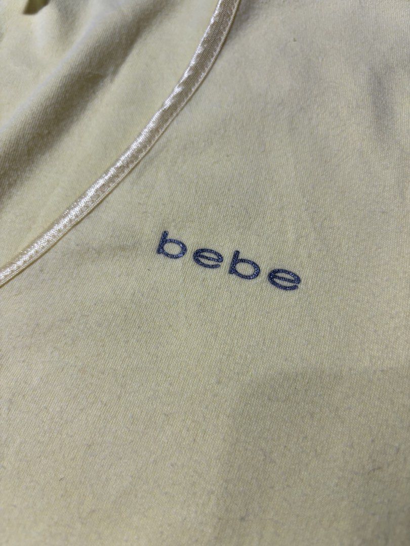 Vintage Bebe Yellow V-Neck Tee Size L (Category: Shirts) located in Cabuyao City. Submitted by macnthrifts. (Listing ID 1464841785, Image 2). Description: - Brand: Bebe - Size: Large (Made in U.S.A.) - Color: Bright yellow - Material: Super soft fabric - Details: V-neck with satin trim, short sleeves, and small sparkly logo on the chest - Style: Great retro piece.