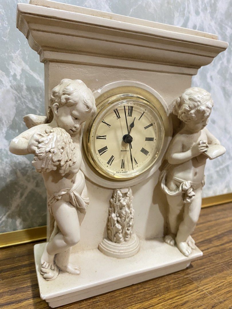 Vintage Neoclassical Table Clock Cherub Mantle Clock (Category: Clocks) located in Calamba. Submitted by chebvintagedepot (Listing ID 1464806735, Image 2). Description: [B24-02] This Cherub Mantle Clock has a neoclassical design inspired by the architecture and decorative style of the French chateau at Versailles. It features twin cherub figures beside the clock, giving it the look of a decorative architectural sculpture. It is battery-operated a