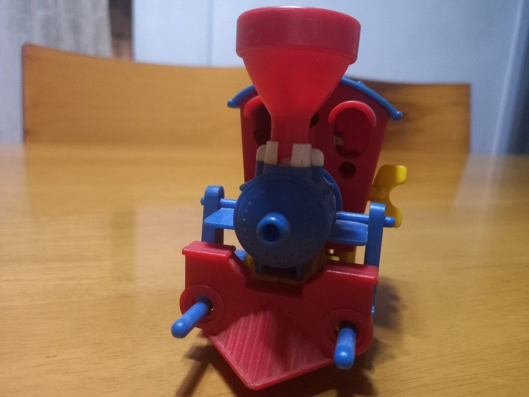 vintage plastic wind-up toy train engine (Category: Kids Toys) located in Manila. Submitted by riaring88 (Listing ID 1464870195, Image 2). Description: - Vibrant design: Red cab, blue roof, yellow wheels, and red funnel chimney - Fun conductor graphic printed on the side window - Perfect for vintage toy collectors - Condition: Good, **wind-up mechanic doesn't function. *** .