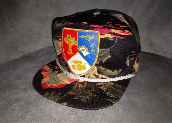 Vintage SAN SUN Black Tropical Sunset & Shield Patch Snapback Hat (Category: Caps & Hats) located in Binangonan. Submitted by yuristalin888 (Listing ID 1464780950, Image 2). Description: Add a unique, retro statement piece to your wardrobe with this vintage SAN SUN snapback hat. It features an all-over tropical sunset and palm tree pattern in shades of black, pink, orange, and green. The front is highlighted by a distinctive multi-colored embroid
