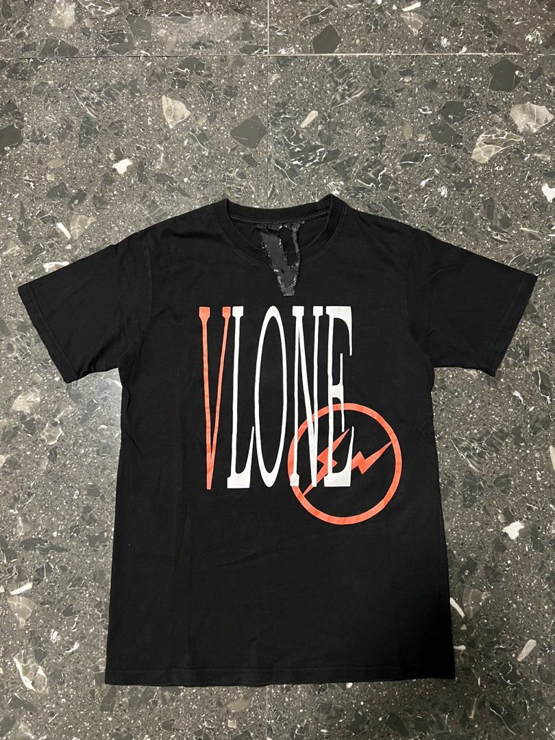 Vlone x Fragment Design Black Tee (Category: Tshirts & Polo Shirts ) located in San Fernando. Submitted by justin_sy (Listing ID 1464887660, Image 1). Description: - Authentic Vlone x Fragment Collaboration - Color: Black, Short Sleeve - Size: Large - Front: Large vertical branding with circle lightning bolt graphic - Back: Matching oversized Vlone bolt logo - Details: Signature V logo inner collar tag, side-seam size and care labels - Material: 