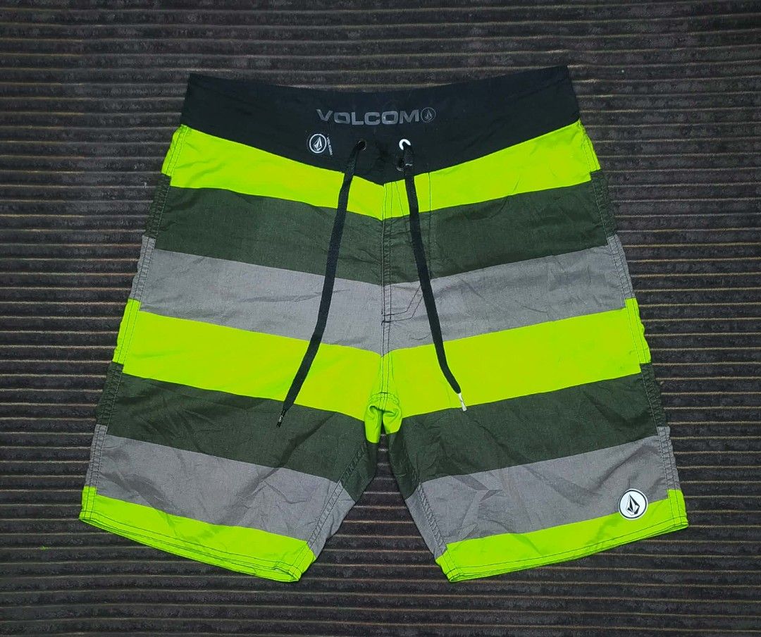 Volcom Men's Striped Board Shorts Swim Trunks (Category: Swim Trunks & Board Shorts) located in Manila. Submitted by norathrifted (Listing ID 1464797598, Image 1). Description: - Brand: Volcom - Design: Horizontal stripes in green, grey, and neon yellow - Waistband: Black with adjustable drawstring and branded metal aglets - Pockets: Single back pocket with flap and button closure - Details: Volcom logo patches on the front leg and back pocket - 