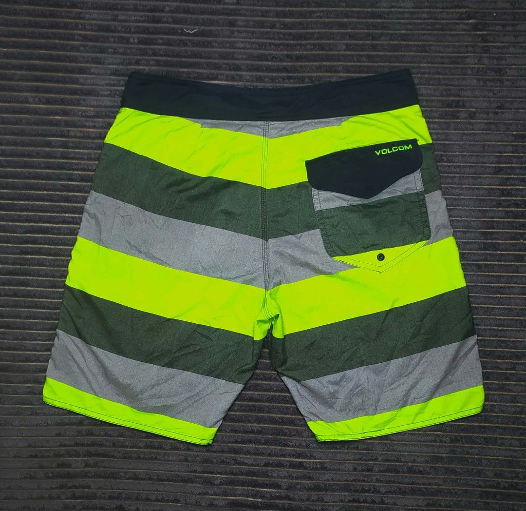 Volcom Men's Striped Board Shorts Swim Trunks (Category: Swim Trunks & Board Shorts) located in Manila. Submitted by norathrifted (Listing ID 1464797598, Image 2). Description: - Brand: Volcom - Design: Horizontal stripes in green, grey, and neon yellow - Waistband: Black with adjustable drawstring and branded metal aglets - Pockets: Single back pocket with flap and button closure - Details: Volcom logo patches on the front leg and back pocket - 