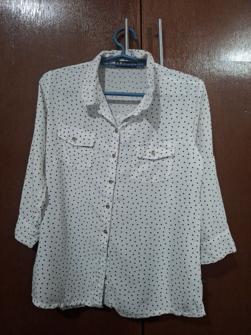 White Button-Up Blouse with Black Square Pattern (Category: Blouses) located in Quezon City. Submitted by 042361 (Listing ID 1464833041, Image 1). Description: - Color/Pattern: White with small black square pattern - Style: Long-sleeve button-up blouse with pointed collar - Features: Front button closure and two buttoned chest pockets - Fabric: Lightweight and comfortable - Fit: Standard fit, regular length - Versatility: Perfect for office wear 