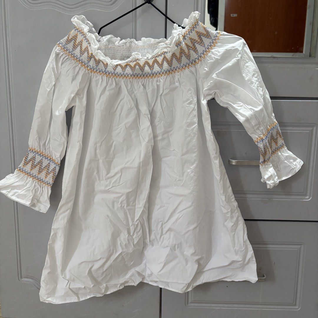 White Embroidered Smocked Off Shoulder (Category: Longsleeves) located in Binan City. Submitted by myprelovedhaul (Listing ID 1464926051, Image 2). Description: This white off-the-shoulder peasant blouse features charming multicolored zig-zag embroidery along the smocked neckline and cuffs..