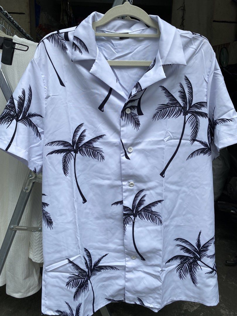 White Palm Tree Print Short Sleeve Button Up Shirt (Category: Tshirts & Polo Shirts ) located in Pateros City. Submitted by shin_0221 (Listing ID 1464880436, Image 1). Description: - Style: Camp collar button-up - Design: All-over black palm tree pattern on white - Material: Lightweight fabric - Ideal for: Warm weather and beach trips - Fit: Standard.