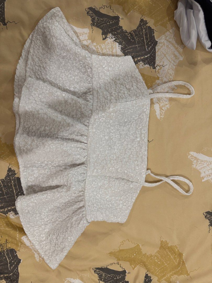 White textured peplum top (Category: Sleeveless) located in Quezon City. Submitted by sonnythehedge (Listing ID 1464775343, Image 1). Description: - Color: White with tiny all-over floral pattern - Style: Cropped cami top with a flared ruffled peplum hem and thin shoulder straps - Material: Textured fabric, lightweight and breathable - Fit: Flattering cropped length - Versatility: Great basic piece for hot weather, easy to match with high-waisted