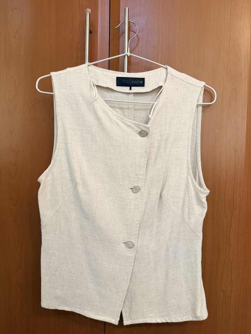 Zara Beige Asymmetric Button Vest Top Size M (Category: Sleeveless) located in Quezon City. Submitted by savjel08 (Listing ID 1464777789, Image 1). Description: - Brand: Zara - Color: Beige - Size: M - Origin: Made in Morocco - Design: Asymmetric front with 3 matching buttons - Material: Textured linen-look fabric with clean panel seams - Style: Sleeveless, collarless neckline - Versatility: Great for layering over shirts or wearing solo.