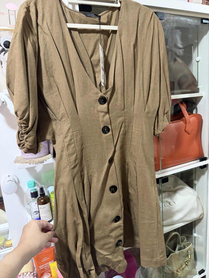 Zara Brown Button-Front Dress Size S (Category: Dresses) located in Manila. Submitted by madsdedios05212 (Listing ID 1464778118, Image 1). Description: - Brand: Zara - Size: Small (Tag still attached) - Original Price: 2,795 PHP - Color: Brown - Details: Short puffed sleeves, V-neckline, large black front buttons, and a fitted waist with subtle pleating - Condition: Brand new with tags.