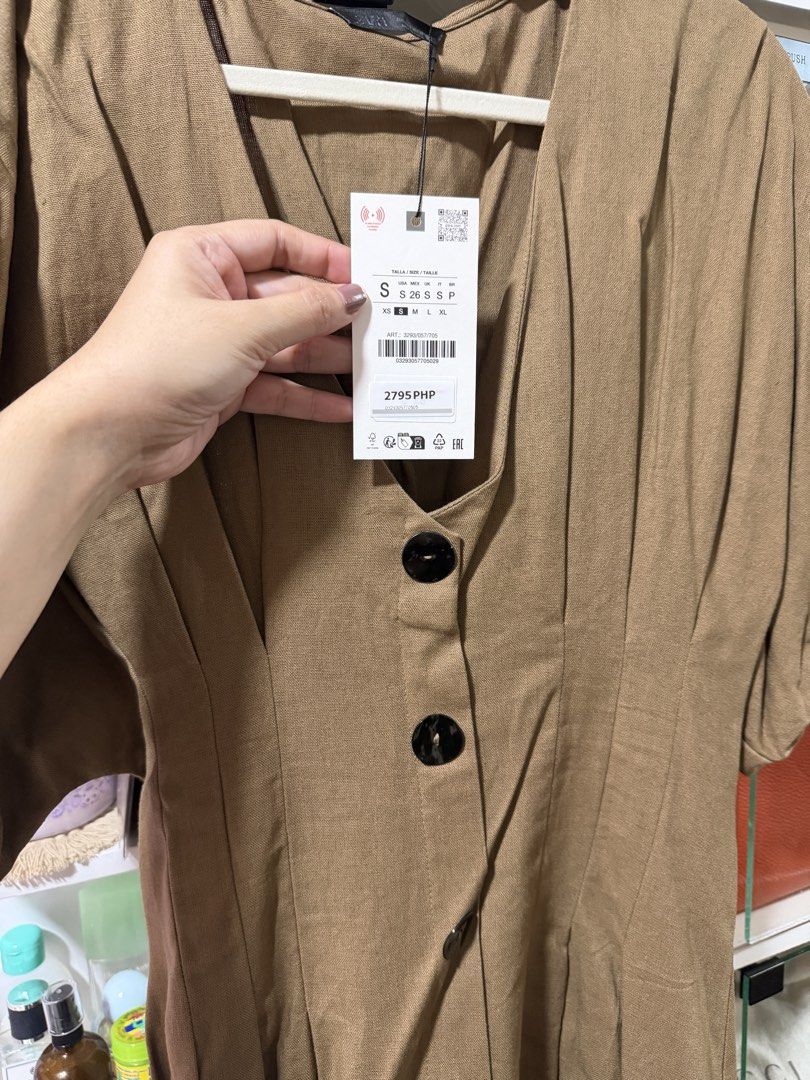 Zara Brown Button-Front Dress Size S (Category: Dresses) located in Manila. Submitted by madsdedios05212 (Listing ID 1464778118, Image 2). Description: - Brand: Zara - Size: Small (Tag still attached) - Original Price: 2,795 PHP - Color: Brown - Details: Short puffed sleeves, V-neckline, large black front buttons, and a fitted waist with subtle pleating - Condition: Brand new with tags.