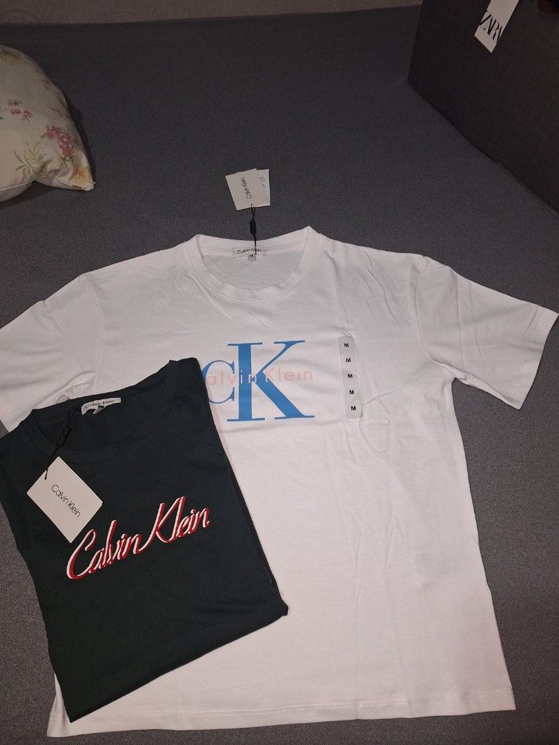 Calvin Klein T-Shirts - White & Green (Category: Shirts) located in Taguig. Submitted by chloe_clothingco. (Listing ID 1459437597, Image 1). Description: - brand new Calvin Klein t-shirts - Size: Large (L) and med - Color 1: White with blue CK logo - Color 2: Dark green with red and white script logo - Both shirts have original tags still attached - Excellent basic pieces for everyday wear.