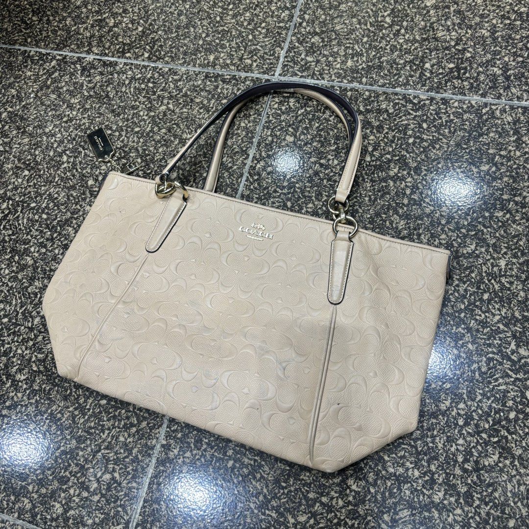 Coach Embossed Monogram Tote Bag Beige (Category: Luxury Bags & Wallets) located in Manila. Submitted by thrifttressure (Listing ID 1459405521, Image 3). Description: - Authentic Coach tote bag - Neutral beige color - Signature Coach monogram embossed all over - Zip top closure - Two shoulder straps - Gold hardware details - Small mark on front (visible in last photo) - Spacious interior for essentials.