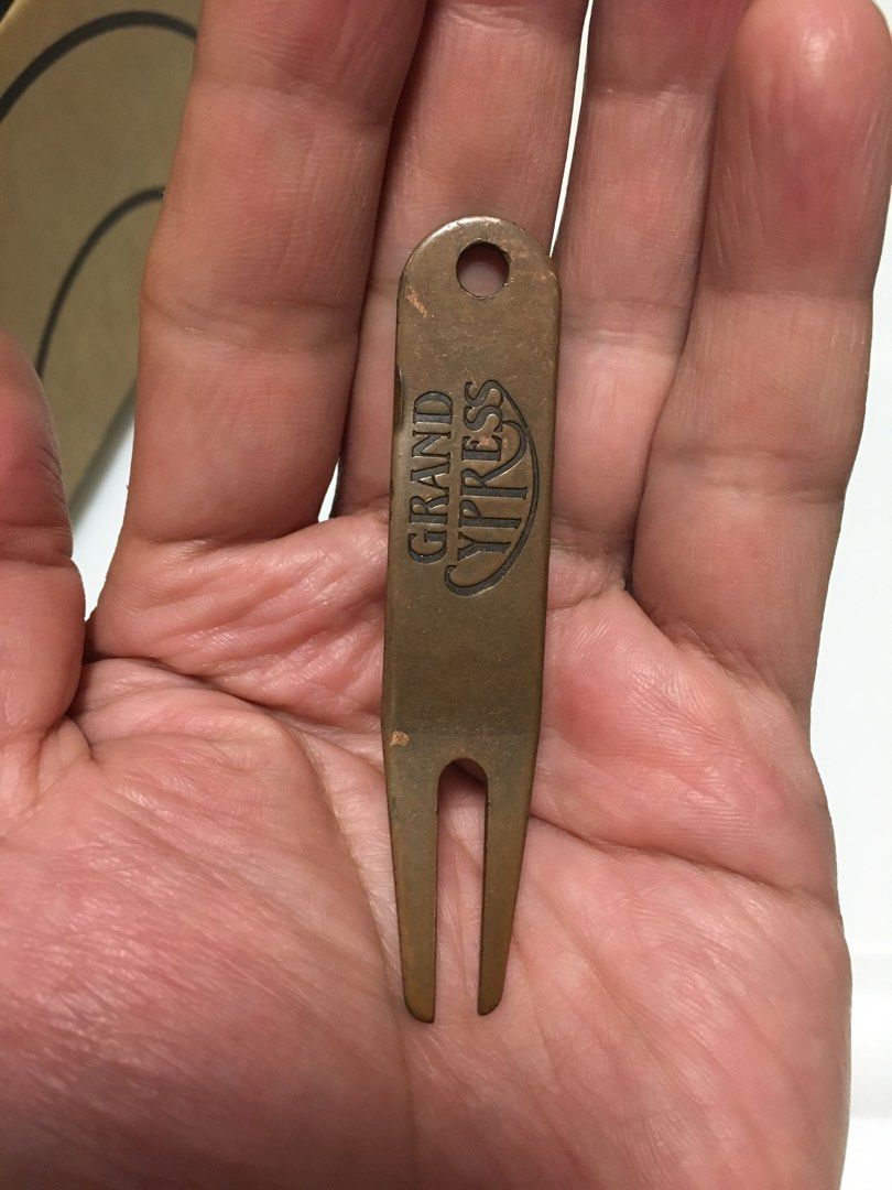Grand Cypress Golf Divot Repair Tool (Category: Other Sports Equipment and Supplies) located in Pasay City. Submitted by gilbertso62551 (Listing ID 1459409228, Image 2). Description: - Bronze colored golf divot tool - Features embossed 'Grand Cypress' logo - Small hole for keychain or bag attachment - Essential accessory for golfers - As is,where is.