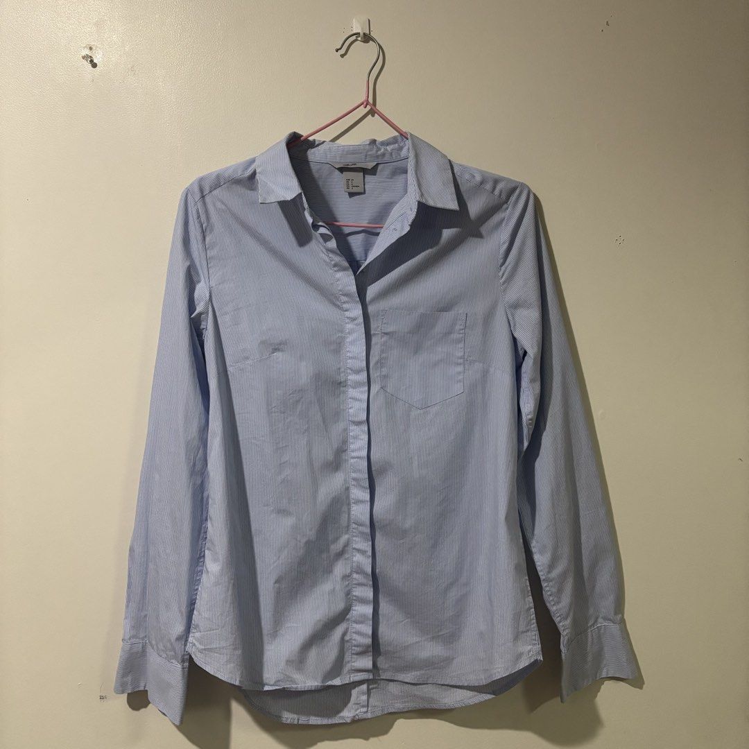 H&M Pinstriped Blue Polo Longsleeve (Category: Longsleeves) located in Binan City. Submitted by myprelovedhaul (Listing ID 1459409827, Image 2). Description: The item in the image is a light blue and white fine pinstriped button-down shirt from H&M. It features a classic spread collar, a left patch pocket, long sleeves with buttoned cuffs, and a gently rounded hemline..