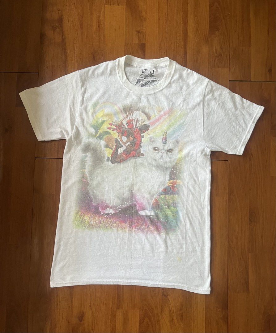Marvel Deadpool Riding Unicatt Graphic T-Shirt (Category: Tshirts & Polo Shirts ) located in Lipa City. Submitted by alexcollectionco (Listing ID 1459447827, Image 1). Description: Deadpool riding a winged unicorn cat (Unicatt) against a rainbow galaxy background. Printed on a soft white cotton-poly blend tee. Brand: Marvel Origin: Made in Honduras Material: 50% Cotton / 50% Polyester Color: White Tag Size: Small Measurements: Pit to Pit / Width: