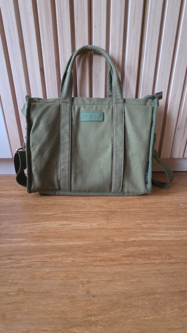 Olive Green Canvas Tote Bag with Shoulder Strap (Category: Tote Bags) located in Mandaluyong City. Submitted by loijiminigo (Listing ID 1459308999, Image 1). Description: - Olive green canvas tote bag - Top handles and detachable shoulder strap - Zips closed for secure main compartment - Interior zippered pockets - Durable material - Ideal for everyday use or travel FREE SF FOR PURCHASES 1200 AND ABOVE.