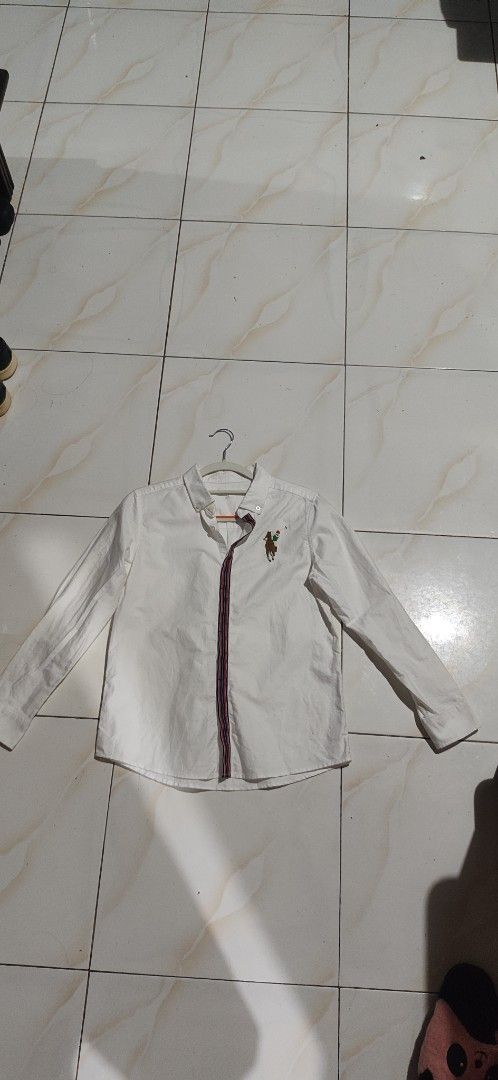 Polo Sport White Button Down Shirt Size 12 (Category: Tshirts & Polo Shirts ) located in Villasis. Submitted by znivvfinds (Listing ID 1459421017, Image 1). Description: - Brand: Polo Sport - Color: White - Style: Long-sleeved button-down shirt - Features: Classic polo player embroidery on chest, striped trim detail on front placket - Size: 12 - Occasion: Great for casual or smart-casual wear.