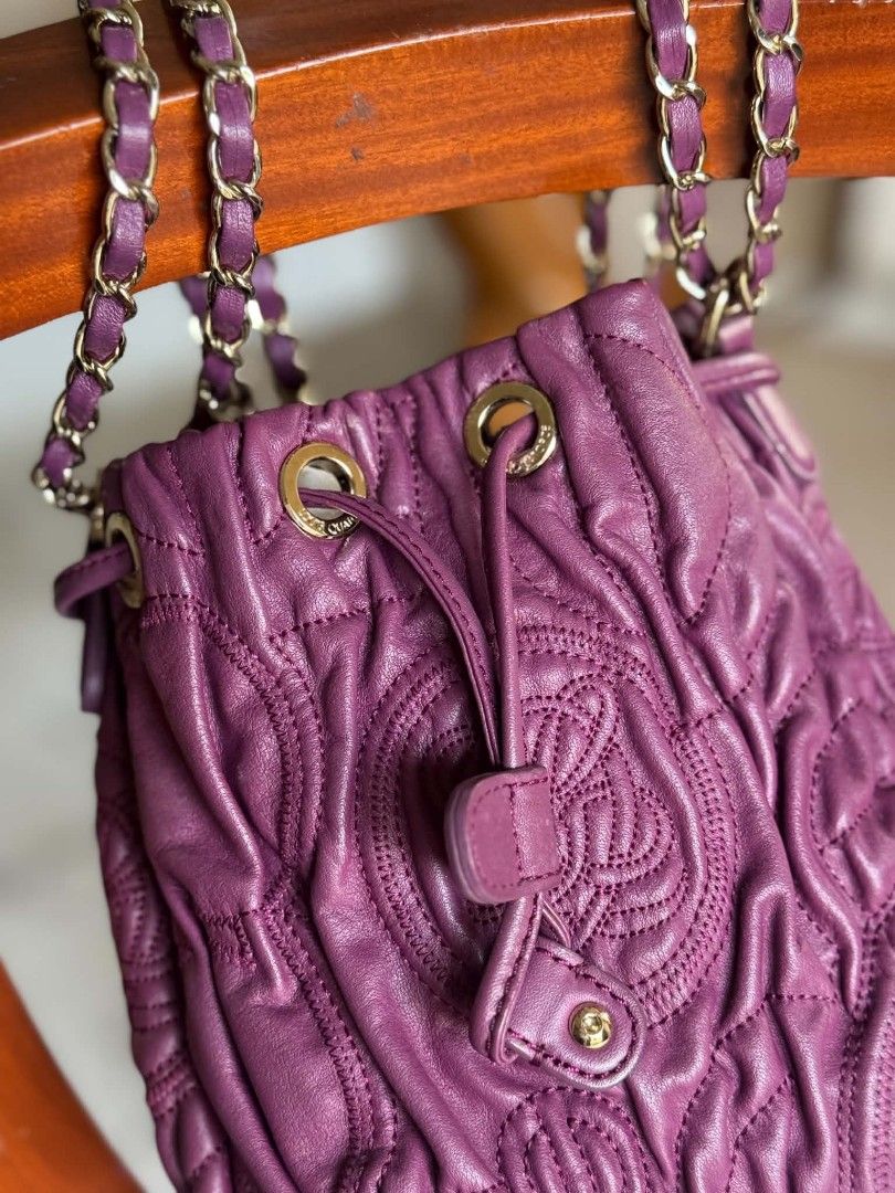 Purple Leather Drawstring Bucket Bag with Chain Strap (Category: Cross-body Bags) located in Bacolod City. Submitted by vintage_vogue6100 (Listing ID 1459414013, Image 3). Description: - Stylish purple leather drawstring bucket bag - Features a chic quilted pattern - Embossed logo detail for a touch of luxury - Elegant gold chain strap with comfortable leather accents - Secure drawstring closure with a snap button flap - Versatile design, ideal f