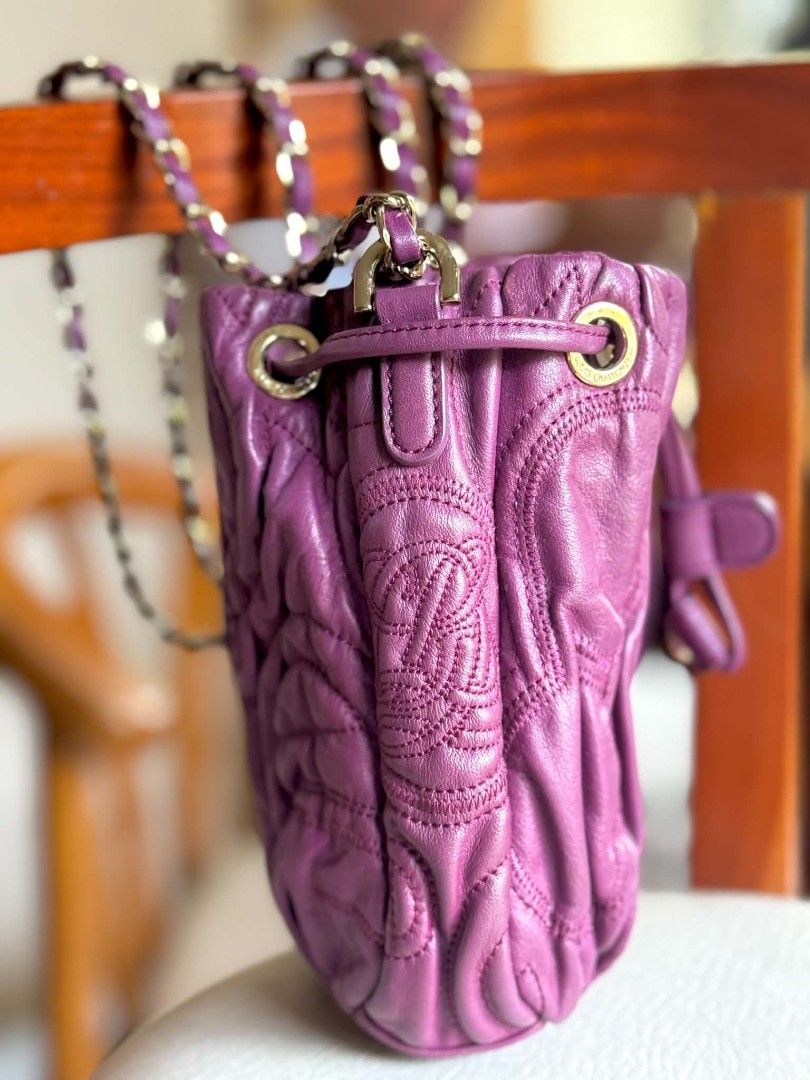 Purple Leather Drawstring Bucket Bag with Chain Strap (Category: Cross-body Bags) located in Bacolod City. Submitted by vintage_vogue6100 (Listing ID 1459414013, Image 2). Description: - Stylish purple leather drawstring bucket bag - Features a chic quilted pattern - Embossed logo detail for a touch of luxury - Elegant gold chain strap with comfortable leather accents - Secure drawstring closure with a snap button flap - Versatile design, ideal f