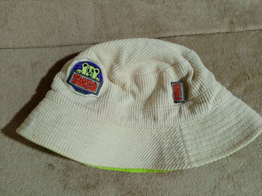 Reversible Bucket Hat - Funky World & FREE (Category: Activewear) located in Castillejos. Submitted by eross07 (Listing ID 1459395430, Image 1). Description: - Super cool reversible bucket hat - Side 1: Cream corduroy with Funky World bear patch - Side 2: Bright lime green with red bear graphic - Both sides feature a small 'FREE' tag - Adjustable drawstring at the back - Great for sunny days and as a fun accessory.