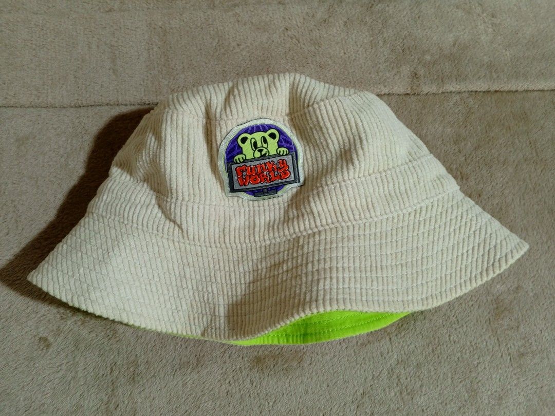 Reversible Bucket Hat - Funky World & FREE (Category: Activewear) located in Castillejos. Submitted by eross07 (Listing ID 1459395430, Image 3). Description: - Super cool reversible bucket hat - Side 1: Cream corduroy with Funky World bear patch - Side 2: Bright lime green with red bear graphic - Both sides feature a small 'FREE' tag - Adjustable drawstring at the back - Great for sunny days and as a fun accessory.