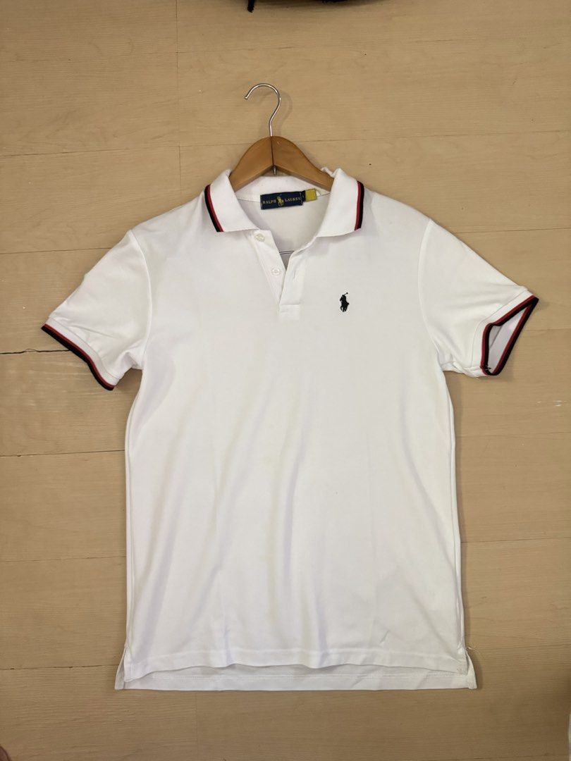 RL Polo Shirt (Category: Tshirts & Polo Shirts ) located in Manila. Submitted by juhjuh (Listing ID 1459345591, Image 1). Description: - Classic white Ralph Lauren polo shirt - Signature embroidered pony logo on chest - Red and navy striped trim on collar and sleeve cuffs - Button-up neckline - Versatile for casual or smart-casual outfits.