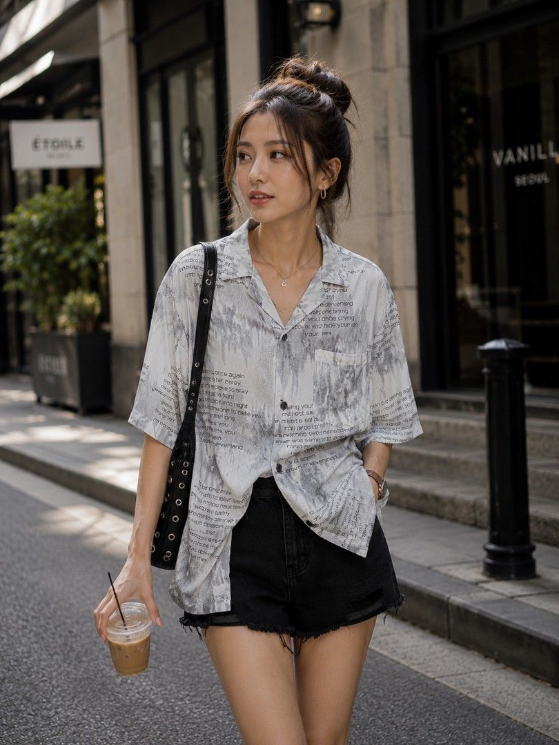 Urban Button-Up Top (Category: Blouses) located in Mexico. Submitted by silverkatie429 (Listing ID 1459289412, Image 1). Description: The blouse is a light-colored button‑up shirt with a loose, relaxed fit. Its standout detail is the scattered printed text across the fabric, giving it a modern, streetwear vibe. Styled with black denim shorts and accessories, it creates a casual yet fashionable look perfect for city strolls..