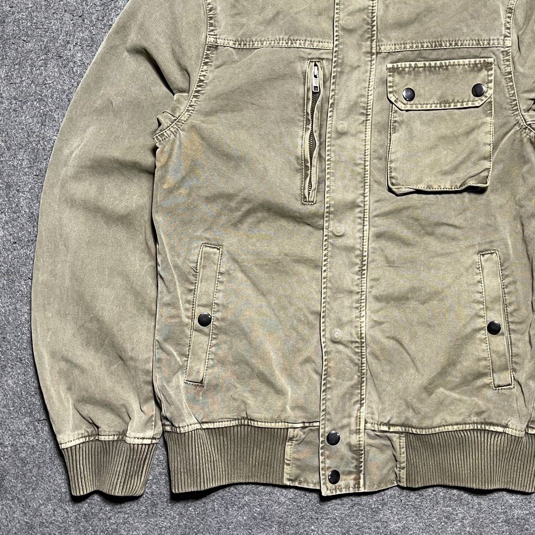 Vintage Corisco washed canvas military bomber jacket (Category: Coats, Jackets and Outerwear) located in Zamboanga. Submitted by rag_20 (Listing ID 1459462789, Image 3). Description: Vintage Corisco washed canvas military bomber jacket It features a rugged, utility-focused design made from a faded khaki-olive cotton canvas, stylized with prominent ribbed knit trimming at the mock neck collar, waist hem, and cuffs, Asymmetrical multi-pocket layout