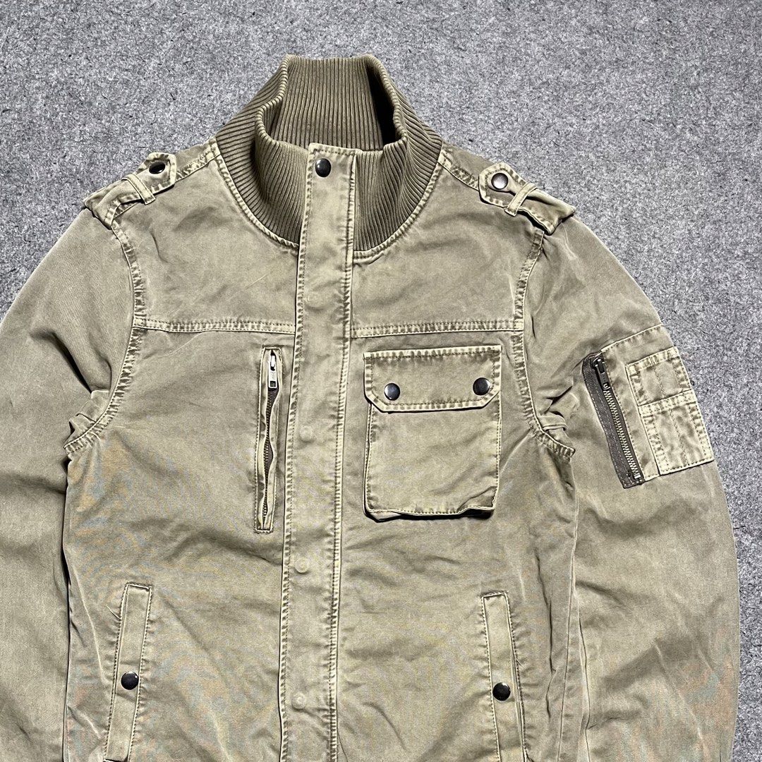Vintage Corisco washed canvas military bomber jacket (Category: Coats, Jackets and Outerwear) located in Zamboanga. Submitted by rag_20 (Listing ID 1459462789, Image 2). Description: Vintage Corisco washed canvas military bomber jacket It features a rugged, utility-focused design made from a faded khaki-olive cotton canvas, stylized with prominent ribbed knit trimming at the mock neck collar, waist hem, and cuffs, Asymmetrical multi-pocket layout
