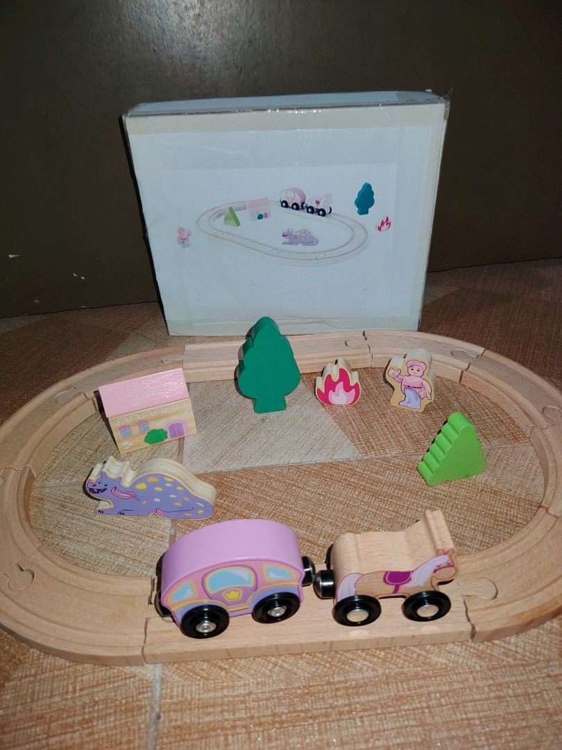 Wooden Train Set with Figures and Accessories (Category: Kids Toys) located in Santiago. Submitted by aceheart0118672 (Listing ID 1459293769, Image 1). Description: - Complete wooden train track set - Includes train with horse carriage, pink carriage, and dragon - Comes with house, trees, person figure, and campfire - Box features an assembly diagram for easy setup - Perfect for imaginative play and building fun for little ones.