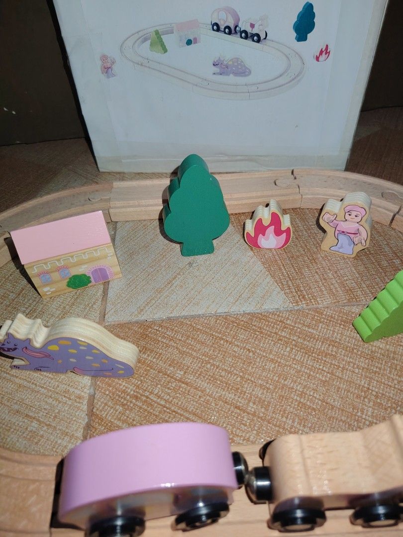 Wooden Train Set with Figures and Accessories (Category: Kids Toys) located in Santiago. Submitted by aceheart0118672 (Listing ID 1459293769, Image 3). Description: - Complete wooden train track set - Includes train with horse carriage, pink carriage, and dragon - Comes with house, trees, person figure, and campfire - Box features an assembly diagram for easy setup - Perfect for imaginative play and building fun for little ones.