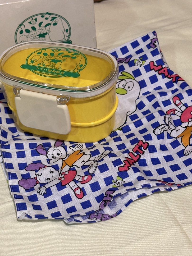 yellow double-layer plastic lunch box with fabric table napkin (Category: Food Organization & Storage) located in Davao. Submitted by favoritepreloved (Listing ID 1459395779, Image 2). Description: 💜 13cm x 7.5cm 💜 with a clear lid and a matching blue-and-white patterned utility cloth 💜 made in Japan.