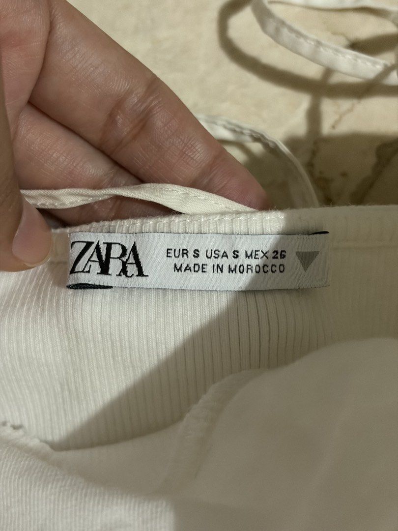 Zara White Ruched Corset Crop Top (Category: Sleeveless) located in Bacoor. Submitted by gailscollections (Listing ID 1459487113, Image 1). Description: Chic Zara white crop top featuring a gathered ruched neckline, delicate spaghetti straps, and a fitted corset-style silhouette. The ribbed stretch fabric and seam detailing create a flattering, feminine shape. Perfect for pairing with jeans, skirts, or tailored trousers for an effortless everyday
