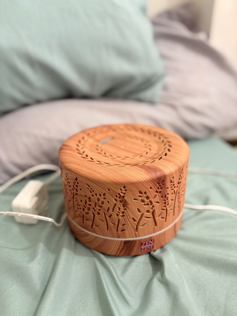 ZenScent Aroma Diffuser with Wood Grain Finish & LED Light (Category: Home Fragrance) located in Pasig City. Submitted by hey_declutter (Listing ID 1459354032, Image 2). Description: - Wooden-look aroma diffuser - Features soothing blue LED light - Comes with a small bottle of 'Rose Petals Orange & Musk' essential oil - Lightly used, excellent working condition - Creates a relaxing atmosphere in any room.