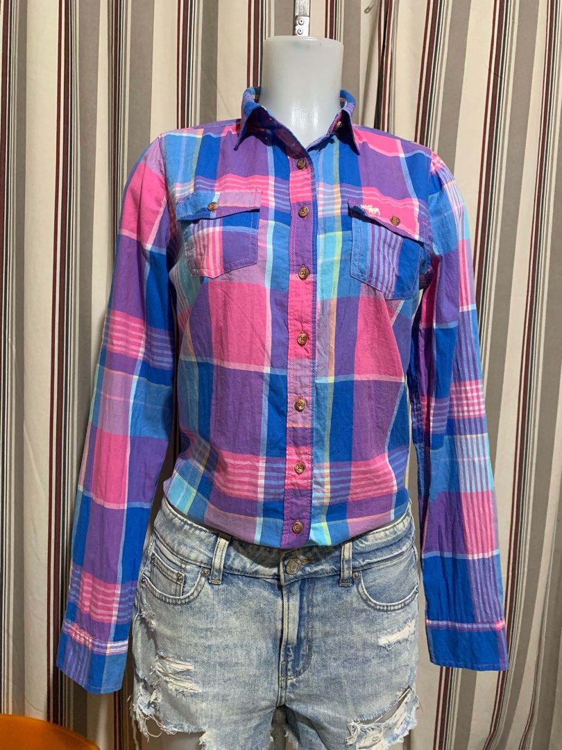 Abercrombie & Fitch Plaid Button-Down Shirt Size M (Category: Tshirts & Polo Shirts ) located in Calapan. Submitted by shakalak (Listing ID 1465100243, Image 3). Description: - Brand: Abercrombie & Fitch - Size: Medium (M) - Pattern: Vibrant pink, blue, and purple plaid - Material: Lightweight and breathable cotton - Features: Long sleeves with button cuffs, classic collar, and dual front chest pockets with button flaps - Condition: Great casual 