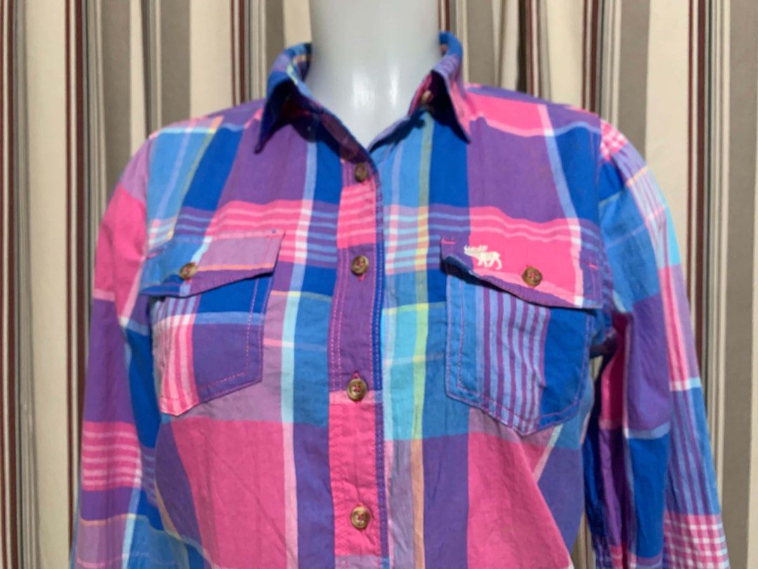 Abercrombie & Fitch Plaid Button-Down Shirt Size M (Category: Tshirts & Polo Shirts ) located in Calapan. Submitted by shakalak (Listing ID 1465100243, Image 2). Description: - Brand: Abercrombie & Fitch - Size: Medium (M) - Pattern: Vibrant pink, blue, and purple plaid - Material: Lightweight and breathable cotton - Features: Long sleeves with button cuffs, classic collar, and dual front chest pockets with button flaps - Condition: Great casual 
