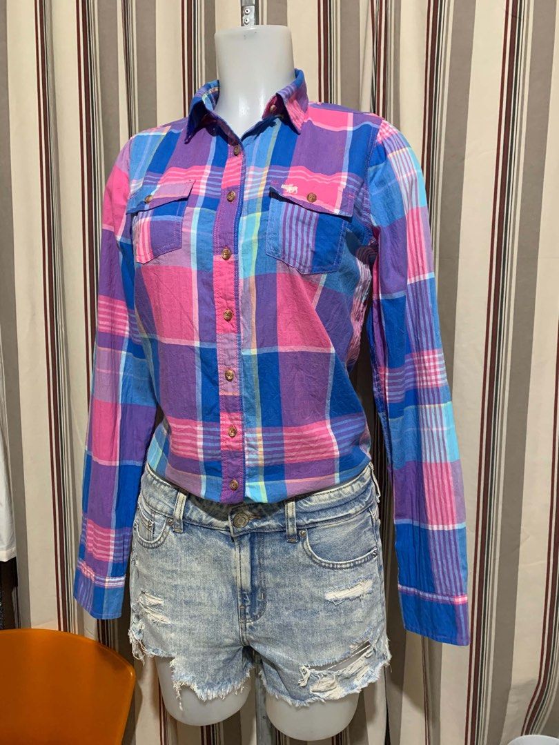 Abercrombie & Fitch Plaid Button-Down Shirt Size M (Category: Tshirts & Polo Shirts ) located in Calapan. Submitted by shakalak (Listing ID 1465100243, Image 1). Description: - Brand: Abercrombie & Fitch - Size: Medium (M) - Pattern: Vibrant pink, blue, and purple plaid - Material: Lightweight and breathable cotton - Features: Long sleeves with button cuffs, classic collar, and dual front chest pockets with button flaps - Condition: Great casual 