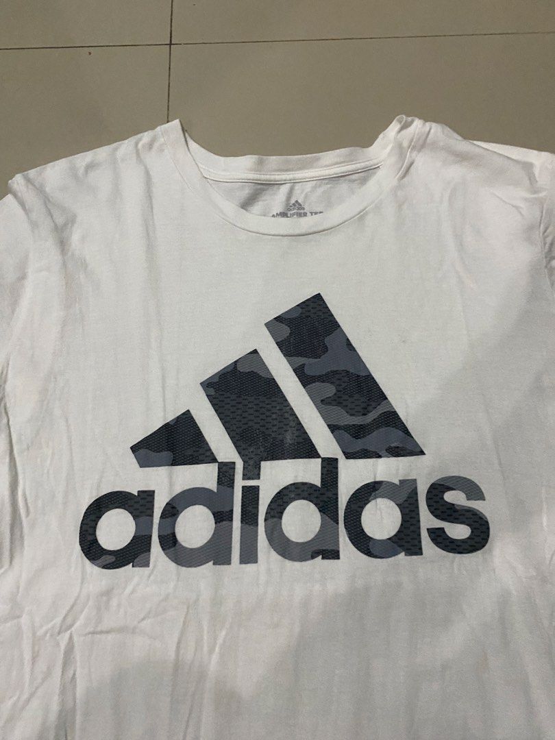 Adidas Amplifier Tee White Camo Logo (Category: Tshirts & Polo Shirts ) located in Makati City. Submitted by dymon_08 (Listing ID 1465105030, Image 2). Description: - Brand: Adidas - Dines W 17.5 L22.5 - Style: Amplifier Tee (Classic crew neck, short sleeves) - Color: White with large camouflage chest logo - Size: XL - Material: 100% cotton (Made in Nicaragua) - Condition: Clean fabric with regular wear, good for everyday casual use.