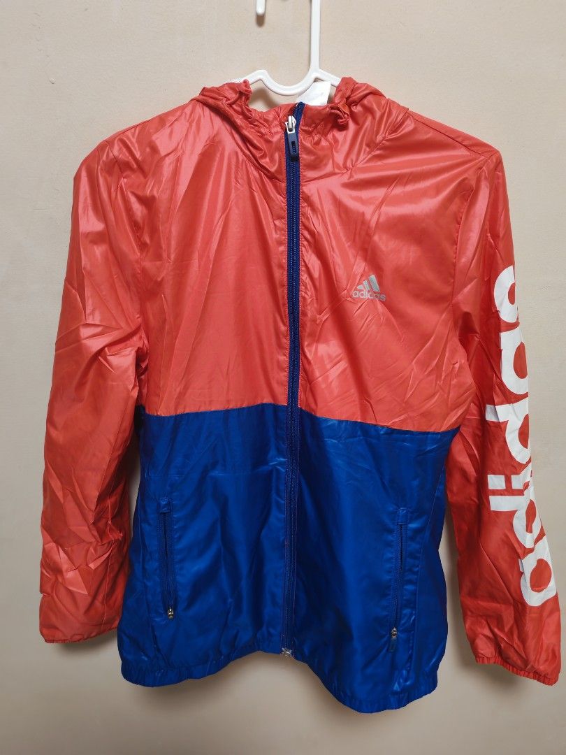Adidas Red Blue Windbreaker Jacket (Category: Coats, Jackets and Outerwear) located in Manila. Submitted by gerwin1990 (Listing ID 1465077241, Image 1). Description: - Authentic Adidas Windbreaker - Color: Red and blue with white details - Features: Full zip front, blue zipper tape, hood, and waist zipper pockets - Design: Large white Adidas lettering on the right sleeve and silver logo on the chest - Material: Lightweight, ideal for workouts or 