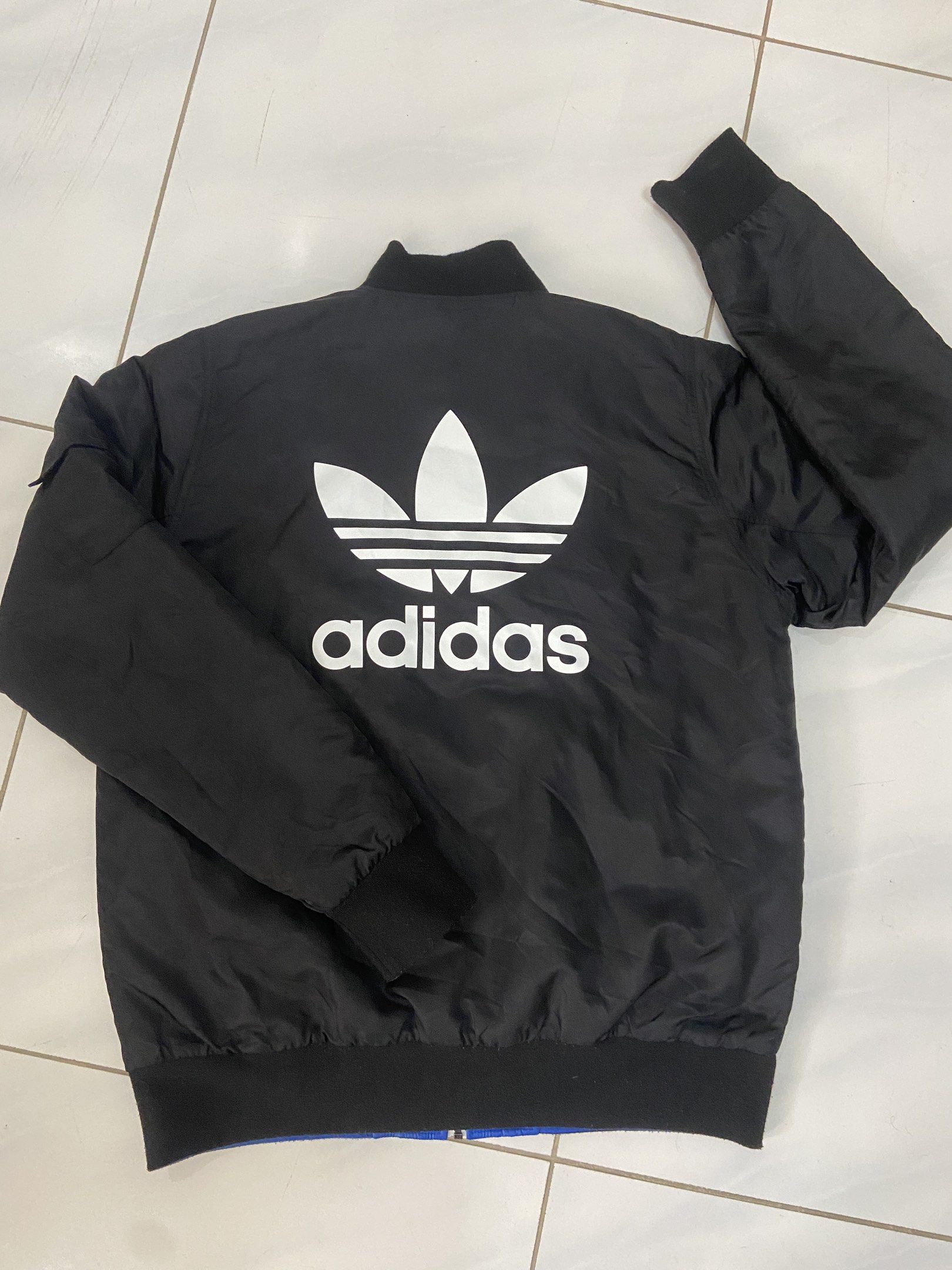 Adidas Reversible Bomber Jacket Black and Blue (Category: Coats, Jackets and Outerwear) located in Pilar. Submitted by romeoabejo54125 (Listing ID 1464983964, Image 2). Description: - Brand: Adidas - Style: Reversible bomber jacket - Side A: Solid black with blue logo hits on chest and back - Side B: Vibrant blue and orange color block with bold arm graphics - Details: Ribbed collar, cuffs, and hem with full zip closure - Condition: Excellent / P